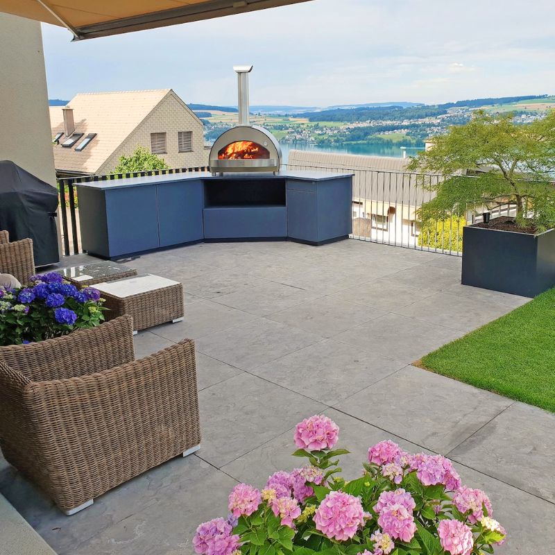 Outdoor patio with Alfa 4 Pizze pizza oven on countertop, furniture, and flowers on a clear day | Outdoor pizza oven for sale