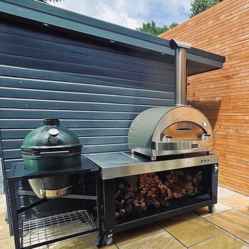 Alfa 4 Pizze oven on an outdoor kitchen setup with an egg grill on a patio.