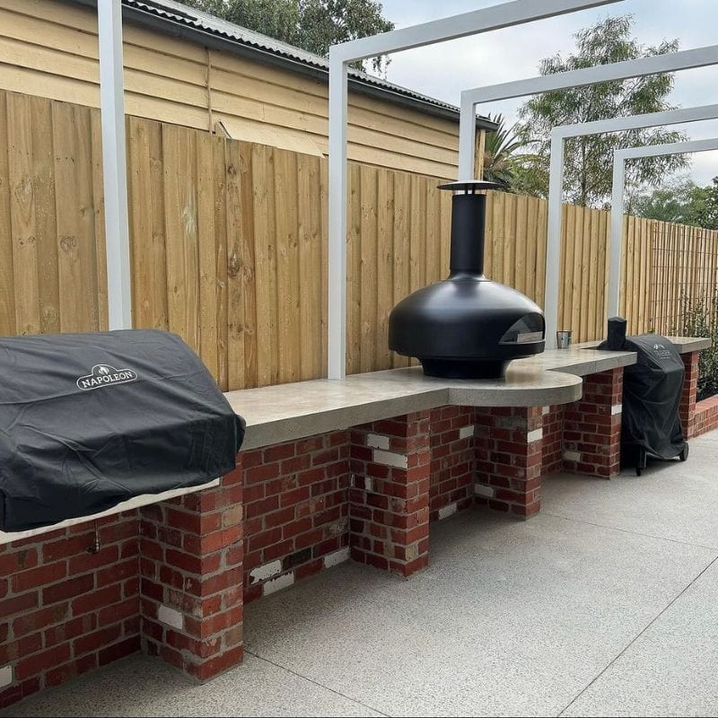 Black Polito Giotto Wood Fired Oven With Bench Stand in Outdoor Patio
