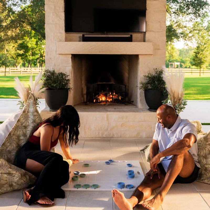 Couple playing checkers on the floor while sitting on the Laze Pillow