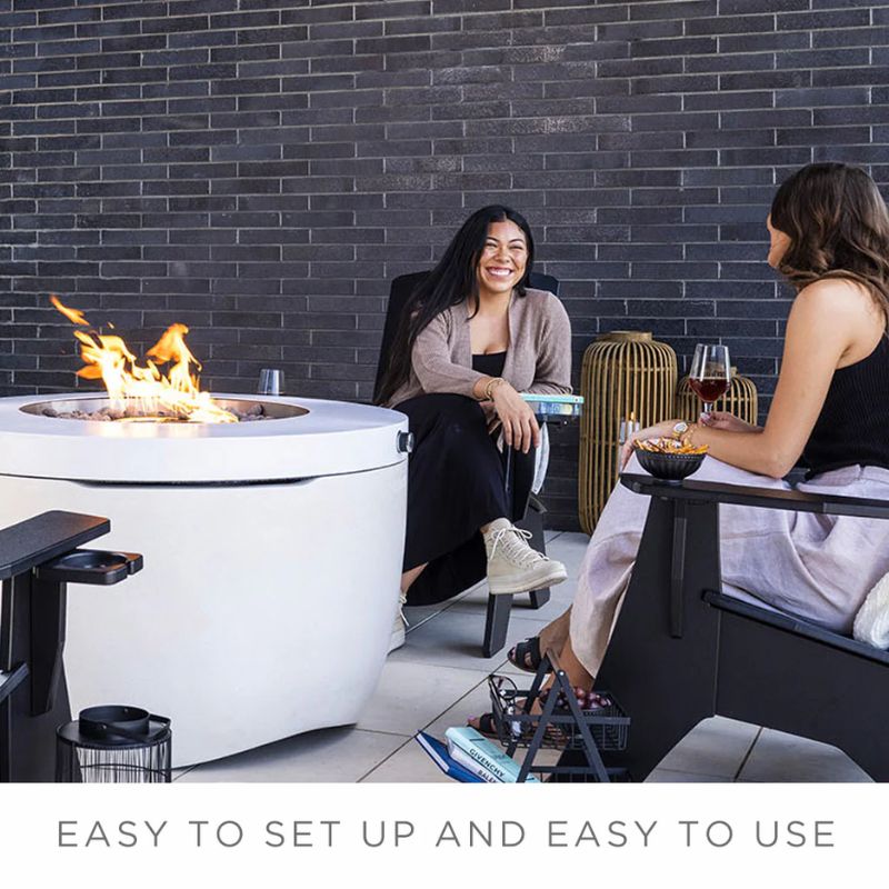Friends chatting beside the Ledge Halo Firepit on a modern backyard patio