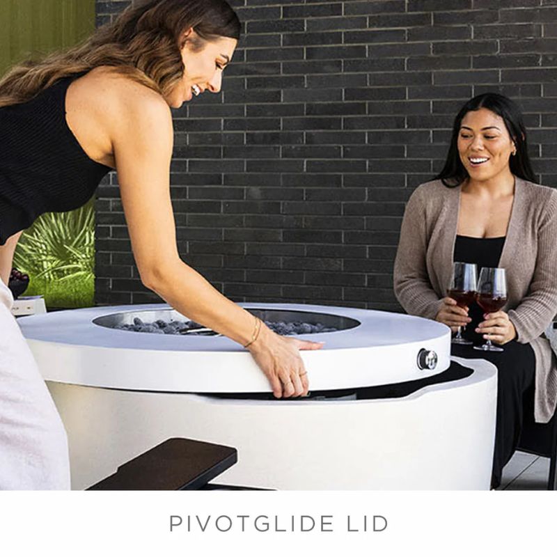 Lady using the pivotglide lid of the Ledge Halo Propane Fire pit