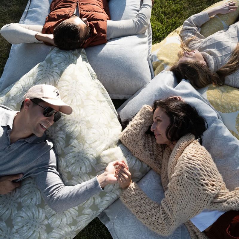 Friends laying on the durable Ledge Laze pillow on the grass