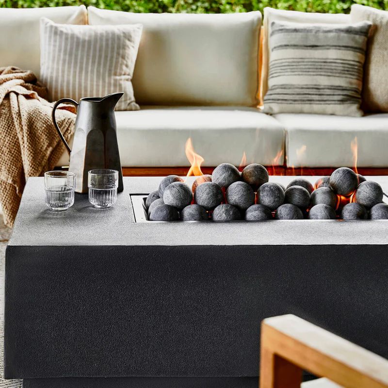 Fire burning over the ceramic stone spheres of the Concrete Fire Pit Table by Outer