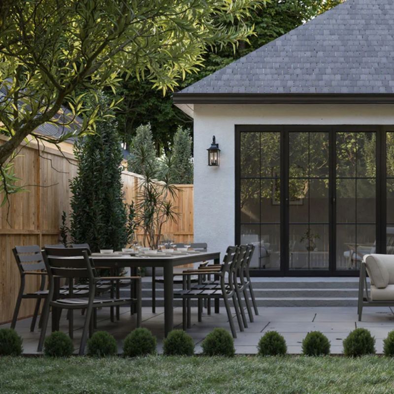 Set of 8 Arm Chairs and a Glacier White OuterStone table set on a patio with surrounding trees and plants