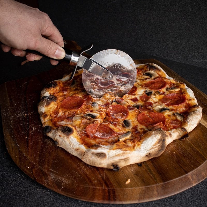 Slicing a pepperoni pizza on the Pinnacolo Acacia Peel