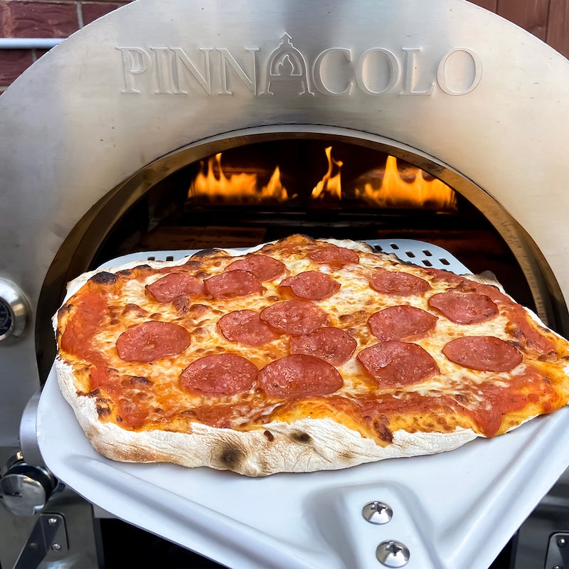 Taking the pepperoni pizza out of the Pinnacolo Ibrido Hybrid Pizza Oven