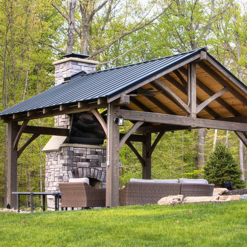 Round Grove outdoor fireplace with arched firebox and stone finish next to a pavillion